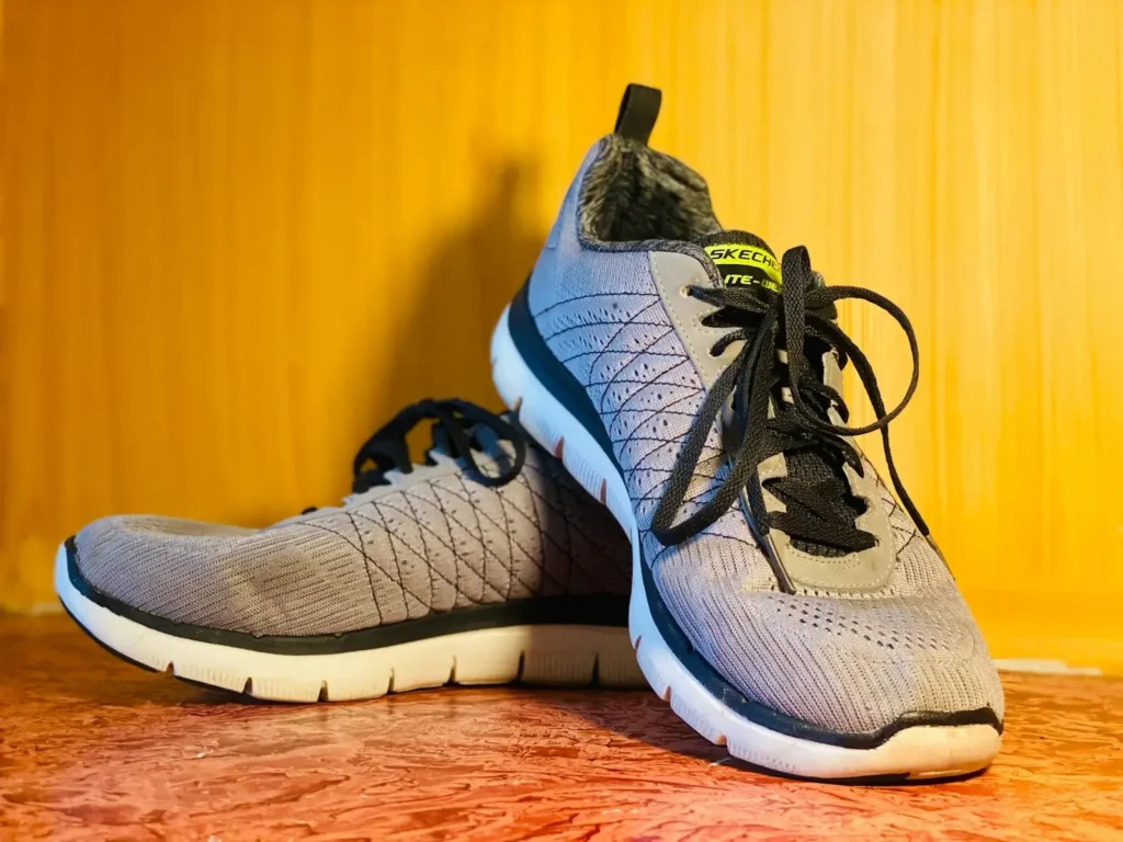 A pair of grey athletic shoes on a wooden surface